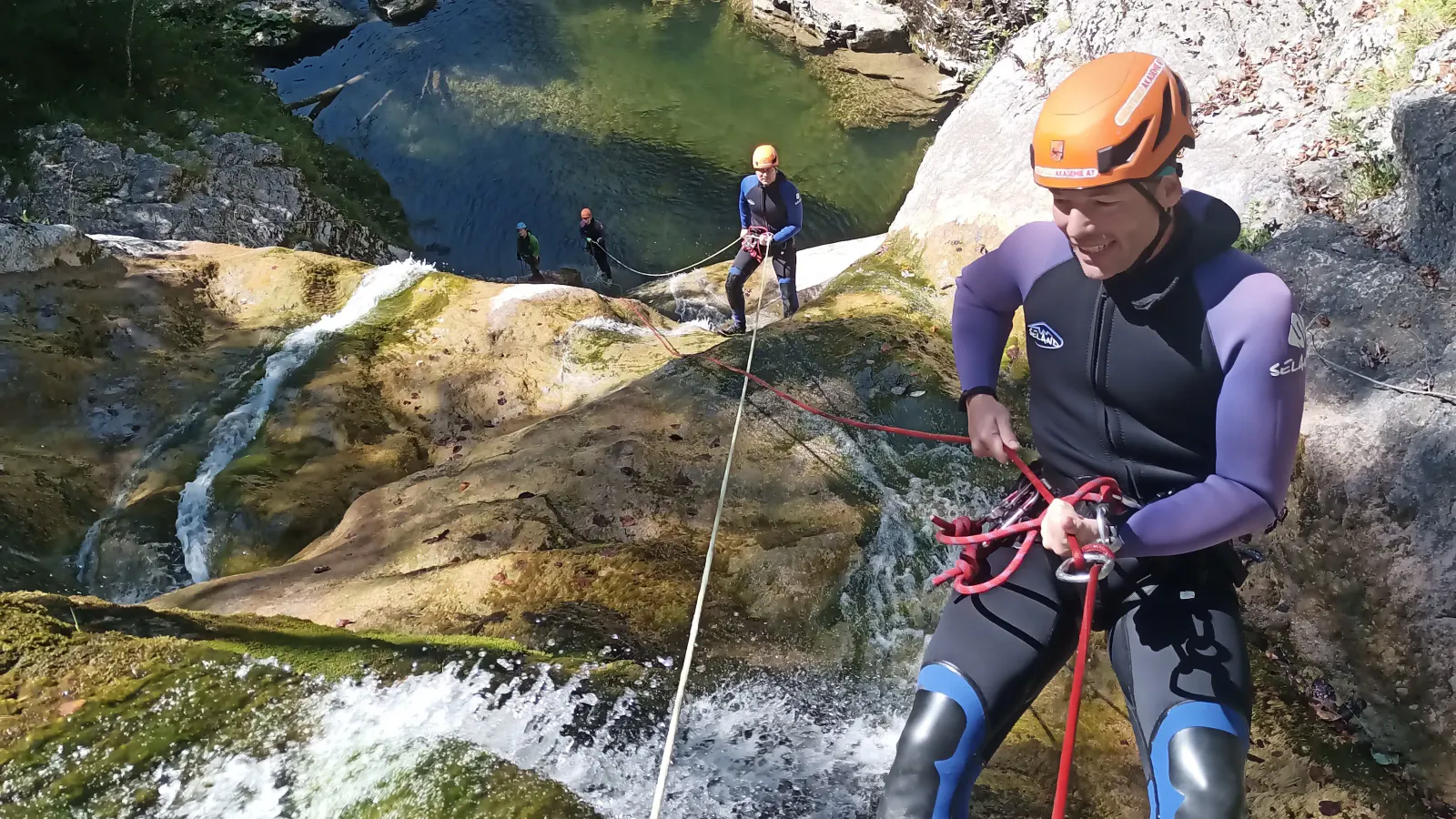 Blick von oben auf mehrere Personen, die entlang eines mehrstufigen Wasserfalls stehen.