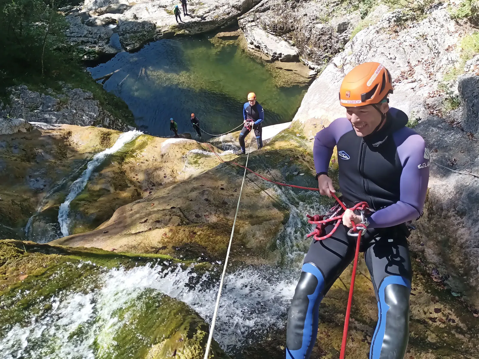 Blick von oben auf mehrere Personen, die entlang eines mehrstufigen Wasserfalls stehen.