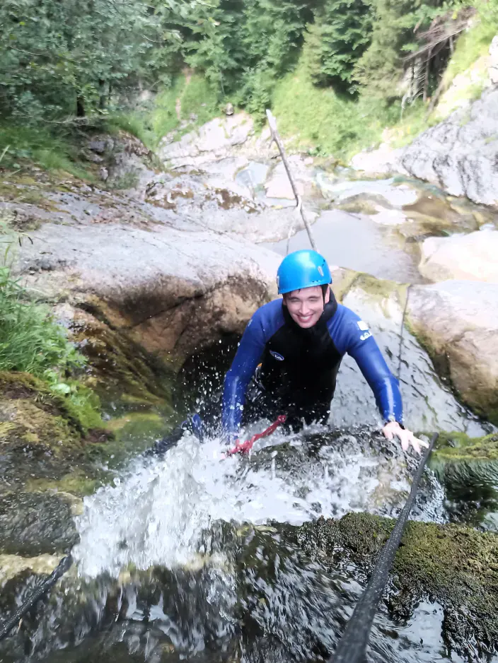 Eine Person klettert einen Wasserfall entlang.